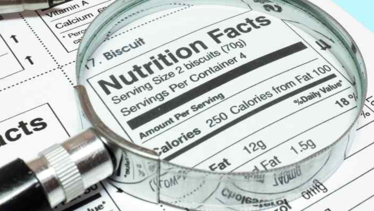 Powiększenie lupą fragmentu tabeli wartości odżywczych na opakowaniu produktu spożywczego, widoczny nagłówek „Nutrition Facts” i niektóre liczby kalorii.