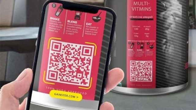 Dłoń trzymająca smartfon z włączonym aparatem skanującym duży czerwony kod QR na etykiecie suplementu diety, w tle widoczna butelka z tą samą etykietą, co pokazuje użycie kodu do uzyskania informacji o multiwitaminach