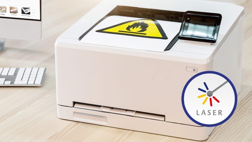 Biała drukarka laserowa zadrukowująca żółty znak ostrzegawczy na arkuszu A4 oraz ikonka trójkolorowego laseru w niebieskim okręgu z podpisem Laser