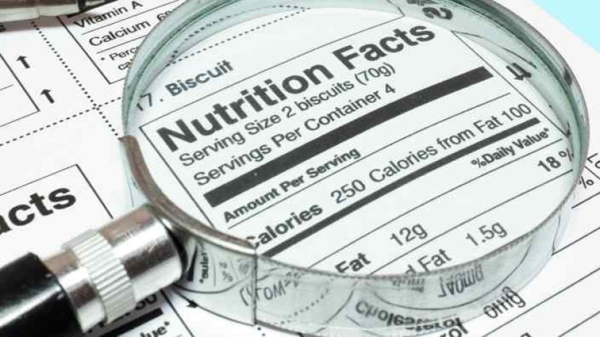 Powiększenie lupą fragmentu tabeli wartości odżywczych na opakowaniu produktu spożywczego, widoczny nagłówek „Nutrition Facts” i niektóre liczby kalorii.