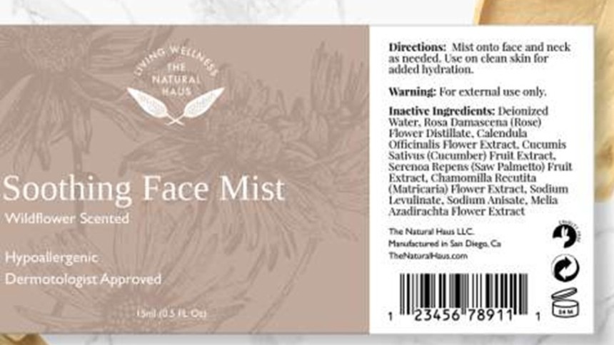 Etykieta produktu "Soothing Face Mist" z informacją o zapachu dzikich kwiatów oraz składem i instrukcją użycia, na tle w odcieniach beżu i bieli z kwiatowym wzorem.