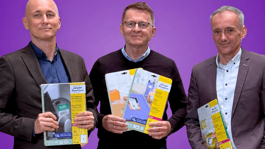 Grafika promocyjna na fioletowym tle z napisem "Samfix & AVERY Zweckform". Poniżej stoją trzej mężczyźni, przedstawiciele firm, uśmiechają się i trzymają w rękach produkty – etykiety Avery Zweckform.
