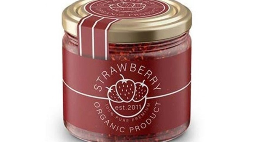 Szklany słoik z dżemem truskawkowym i czerwoną etykietą z napisem "Strawberry organic product" oraz grafiką trzech truskawek.