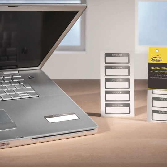 Paczki tabliczek znamionowych obok oznaczonego czarnego laptopa