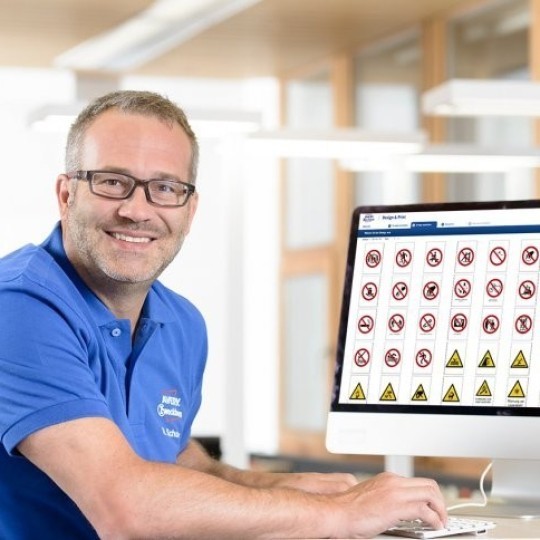 Mężczyzna siedzący przed ekranem komputera na którym wyświetlają się szablony etykiet ostrzegawczych BHP w oprogramowaniu Avery Design&Print