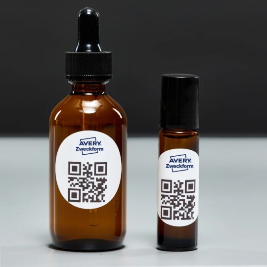 Dwie buteleczki olejków z owalnymi naklejkami z kodem QR