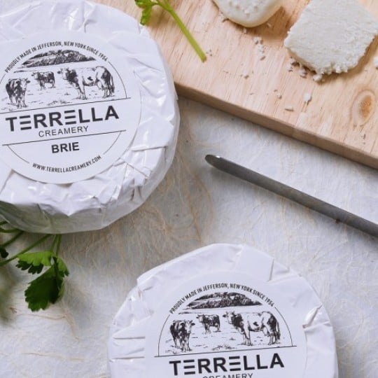 Dwie paczki serka brie z naklejkami z logo