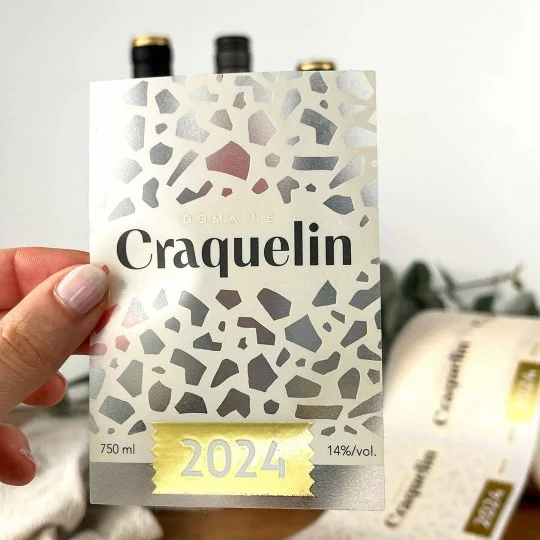 Etykieta na wino z napisem ‘Domaine Craquelin 2024’. Projekt w stylu terrazzo z kolorowymi geometrycznymi kształtami i złotym elementem z rokiem