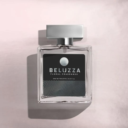 Kwadratowy flakon perfum z metalową zatyczką. Na etykiecie widnieje napis „BELUZZA FLORAL FRAGRANCE”. Flakon stoi na jasnoróżowym tle, cień pada na lewo.