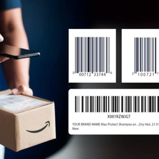 Osoba trzymająca długopis nad kartonowym pudełkiem z logo Amazon. Po prawej stronie znajdują się trzy przykładowe etykiety z kodami kreskowymi - dwie kwadratowe etykiety z kodami EAN/UPC oraz jedna prostokątna etykieta z kodem kreskowym i tekstem opisującym szampon do włosów suchych marki YOUR BRAND NAME Max Protect, 21,9 fl oz.