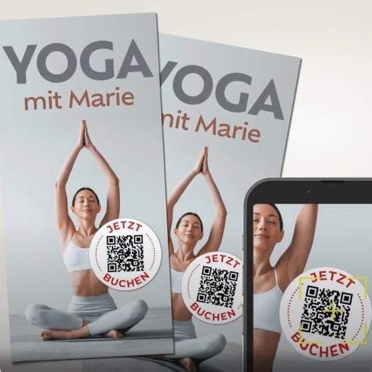 Plakat i ekran smartfona z tą samą reklamą zajęć „YOGA mit Marie”. Na jasnym tle widać kobietę siedzącą po turecku na macie, w sportowym topie i legginsach, z rękami uniesionymi nad głową w pozycji jogi. Na dole po prawej stronie każdego plakatu i na ekranie telefonu widoczny jest okrągły znaczek z napisem „JETZT BUCHEN” oraz kodem QR do rezerwacji zajęć.