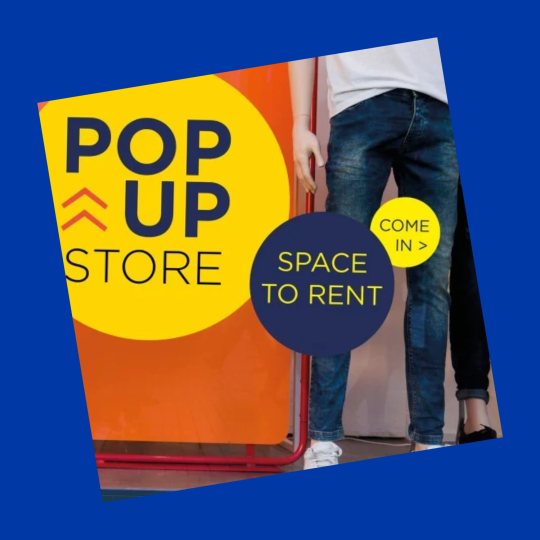 Plakat „POP UP STORE” z informacją „SPACE TO RENT” oraz „COME IN >”, na tle wejścia do lokalu.