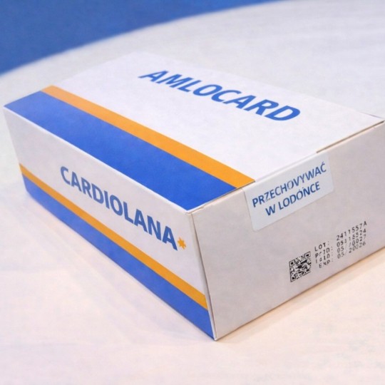  Kartonowe opakowanie leku o nazwie Amlocard / Cardiolana. Na boku pudełka naklejono białą etykietę z napisem "Przechowywać w lodówce" oraz kodem 2D.