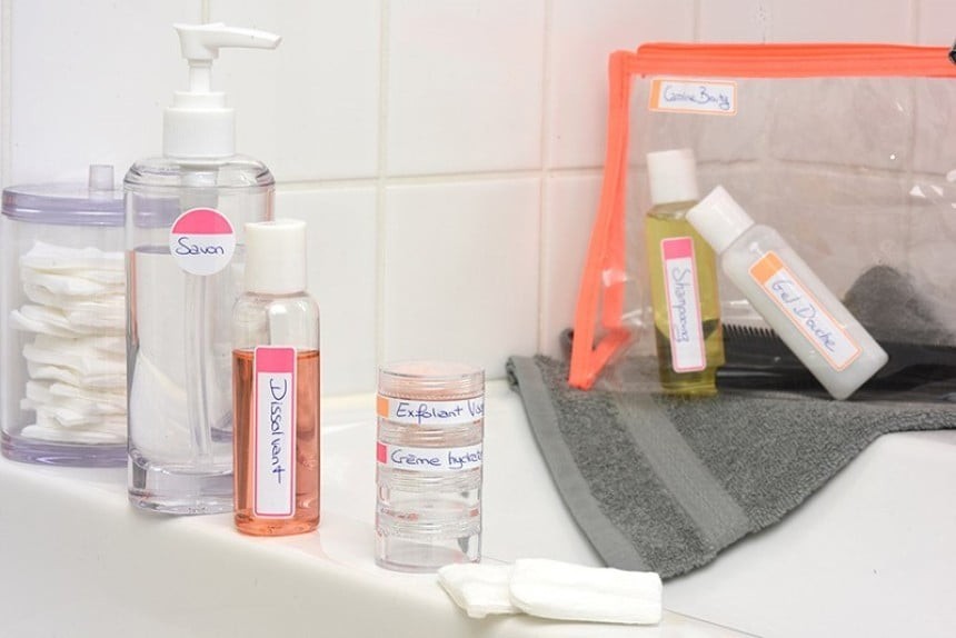 Kosmetyki w podróżniczych buteleczkach z opisami ręcznymi - jedne stojące na stole, drugie zapakowane w plastikowy przezroczysty woreczek