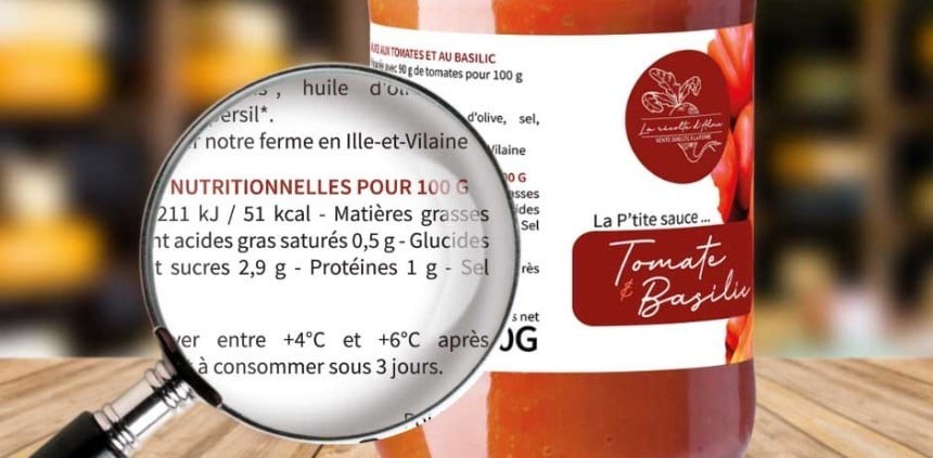  Zbliżenie etykiety sosu pomidorowego z bazylią na słoiku, tekst „Tomate & Basilic”. Przed słoikiem lupa powiększająca fragment informacji o wartościach odżywczych.