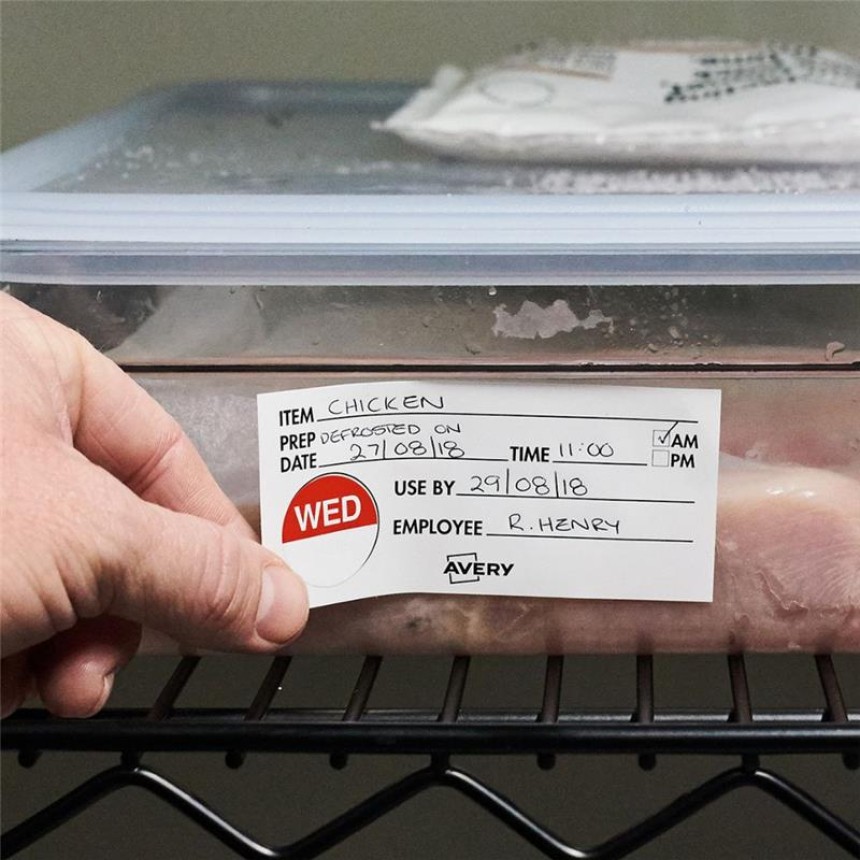 Zbliżenie na plastikowy pojemnik z mięsem z kurczaka o zamkniętym wieczku. Na pojemniku widoczna jest duża etykieta z informacjami: „Chicken”, data rozmrożenia (27/08/18), godzina 11:00, data przydatności do spożycia (29/08/18), imię pracownika (R. Henry). Etykieta ma czerwone pole z napisem „WED”. Po lewej stronie widoczna dłoń osoby trzymającej pojemnik.