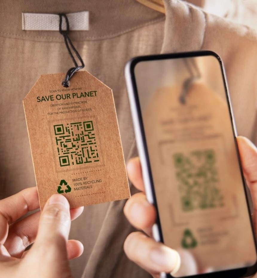 Osoba skanuje smartfonem kod QR z metki ubrania z napisem 'Save our planet' zawierającej informacje o zrównoważonej produkcji