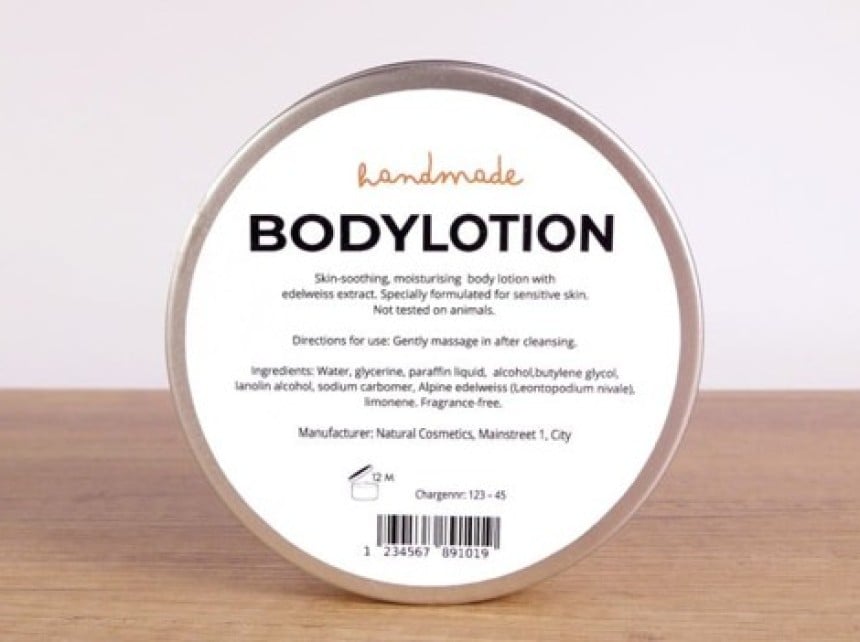 Okrągłe, metalowe opakowanie balsamu do ciała stojące na drewnianym blacie. Na białej etykiecie znajduje się tekst: "handmade BODYLOTION. Skin-soothing, moisturising body lotion with edelweiss extract. Specially formulated for sensitive skin. Not tested on animals. Directions for use: Gently massage in after cleansing. Ingredients: Water, glycerine, paraffin liquid, alcohol, butylene glycol, lanolin alcohol, sodium carbomer, Alpine edelweiss (Leontopodium nivale), limonene. Fragrance-free. Manufacturer: Nat