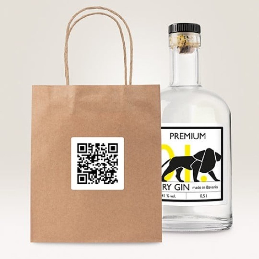 Papierowa torba na zakupy z naklejką z kodem QR, obok butelki ginu. Przykład zastosowania etykiet z kodem QR.