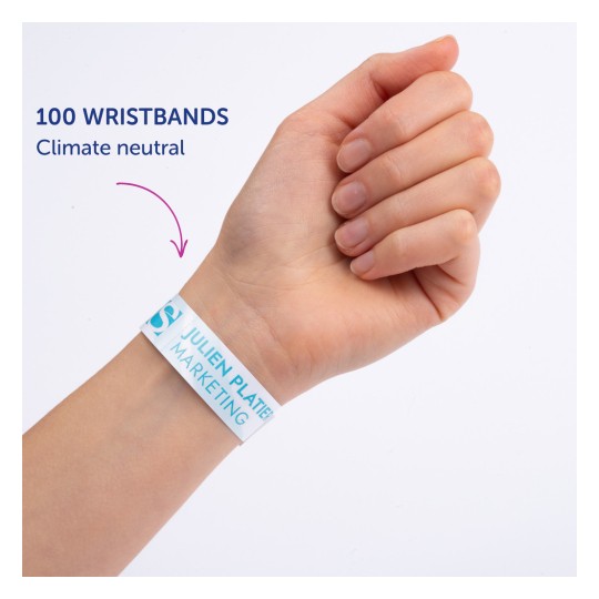 Obraz przedstawia dłoń osoby noszącą opaskę, na której widnieje napis „100 WRISTBANDS Climate neutral” oraz „JULIEN PLATTER MARKETING”.
