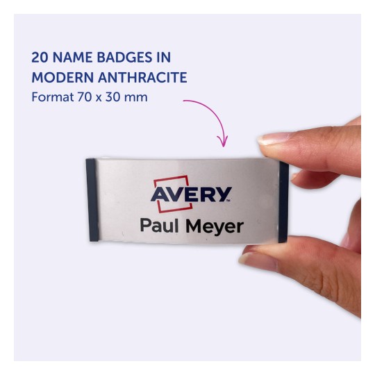 Obraz przedstawia rękę trzymającą identyfikator z napisem „Avery” oraz imieniem „Paul Meyer”, wskazujący, że jest to część zestawu 20 identyfikatorów w nowoczesnym kolorze antracytowym, o wymiarach 70 x 30 mm.