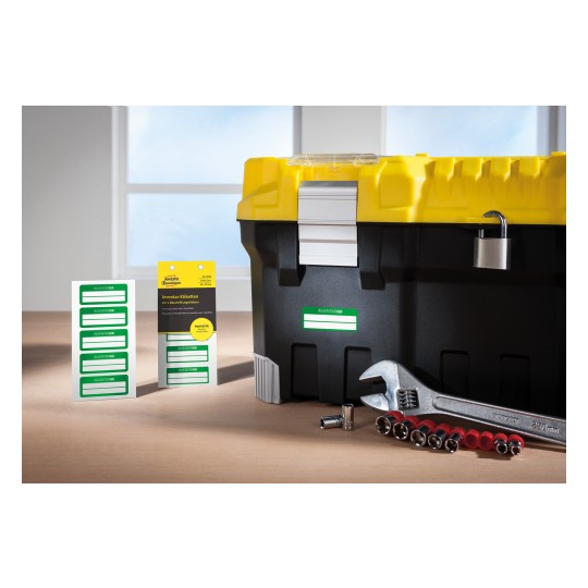 The image shows a black toolbox with a yellow lid, a padlock, some labeling stickers, a wrench, and socket attachments placed on a wooden surface, with natural light coming from a window.
