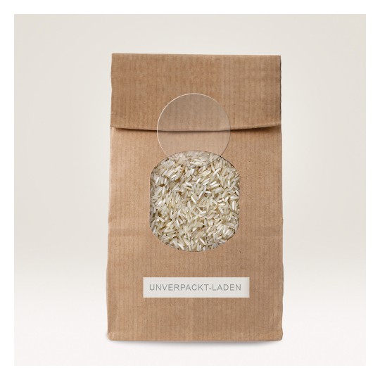 The image shows a brown paper bag with a circular window displaying white rice inside. The bag is labeled 'UNVERPACKT-LADEN.'