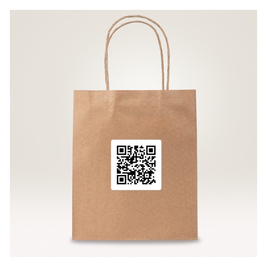 Obraz przedstawia brązową papierową torbę z naklejką z kodem QR. Torba ma dwa skręcone papierowe uchwyty i jest ustawiona na jasnym tle.