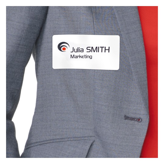 Obraz przedstawia osobę ubraną w szarą marynarkę garniturową z przypiętą plakietką z imieniem 'Julia SMITH Marketing'.