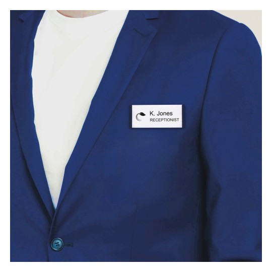 Obraz przedstawia osobę ubraną w niebieski blazer na białym t-shircie, z identyfikatorem z napisem 'K. Jones RECEPCJONISTA' przypiętym do blazera.