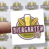 Kwadratowa naklejka z emblematem kufla z piwem i napisem Biergarten z arkuszem tych naklejek w tle