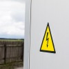 Żółty trójkątny znak ostrzegawczy z ikoną błyskawicy naklejony na sprzęt elektryczny