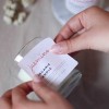 Dłonie naklejające białą kwadratową etykietę na świecę