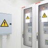 Pudła z instalacją elektryczną oznaczone żółtymi trójkątnymi etykietami ostrzegawczymi