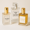 Trzy szklane flakony perfum na jasnym tle: po lewej różowy „Floral Scent”, w środku wyższy „Eau de Cologne”, po prawej bursztynowy „Citrus Perfume”, wszystkie z prostymi, jasnymi etykietami i złotymi zakrętkami.