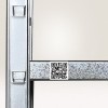 Fragment metalowego regału magazynowego z małą, białą etykietą z kodem QR naklejoną na poziomą belkę, przeznaczoną do skanowania lokalizacji lub produktu.