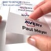 Obraz przedstawia rękę odrywającą etykietę z arkusza, zawierającą nazwisko 'Paul Meyer' i logo 'Avery', z informacją, że łatwo ją oderwać dzięki gładkim krawędziom.