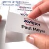 Obraz przedstawia rękę trzymającą kartę z napisem 'Avery' i 'Paul Meyer', co wskazuje, że łatwo ją odłączyć z gładkimi krawędziami. W tle widoczne są liczne karty.
