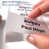 Obraz przedstawia dłoń trzymającą plakietkę z napisem 'Avery Paul Meyer.' Podkreśla łatwość odczepiania plakietki, zwracając uwagę na gładkie krawędzie.