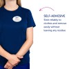 Obraz przedstawia osobę ubraną w granatową koszulę z identyfikatorem z napisem „B. Carlos, Dyrektor Marketingu”. Obok znajduje się tekst opisujący cechę samoprzylepną, która przylega do ubrań i łatwo się usuwa, nie pozostawiając śladów.