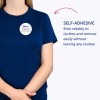 Na obrazie widnieje osoba ubrana w niebieską koszulkę z samoprzylepną plakietką imienną z napisem „B. Carlos, Dyrektor Marketingu.” Tekst podkreśla, że plakietka niezawodnie przylega do ubrania i można ją łatwo usunąć bez pozostawiania śladów.