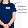 Obraz przedstawia osobę w niebieskiej koszuli z samoprzylepnym identyfikatorem, na którym widnieje napis „B. Carlos, Dyrektor Marketingu.” Tekst podkreśla samoprzylepną cechę identyfikatora, wskazując, że dobrze się trzyma i można go usunąć bez pozostawiania śladów.