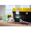The image shows a black toolbox with a yellow lid, a padlock, some labeling stickers, a wrench, and socket attachments placed on a wooden surface, with natural light coming from a window.