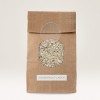 The image shows a brown paper bag with a circular window displaying white rice inside. The bag is labeled 'UNVERPACKT-LADEN.'