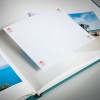 Obraz przedstawia otwarty album ze zdjęciami, z pustą stroną gotową do umieszczenia zdjęcia. Album zawiera obrazy plaży i scenerii oceanicznej, z wyraźnie widoczną pustą stroną.