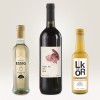 Obraz przedstawia trzy butelki: butelkę octu balsamicznego z jabłek, butelkę czerwonego wina z etykietą 'Night Owl' oraz butelkę likieru śmietankowego. Są ustawione na jasnym tle.