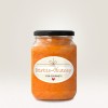 Obraz przedstawia słoik z Kürbis-Chutney z ozdobną etykietą. Chutney ma żywy pomarańczowy kolor, a słoik ma czarną pokrywkę. Na etykiecie na jasnym tle widnieje napis 'Kürbis-Chutney für Gourmets'.