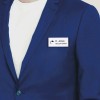 Obraz przedstawia osobę ubraną w niebieski blazer na białym t-shircie, z identyfikatorem z napisem 'K. Jones RECEPCJONISTA' przypiętym do blazera.