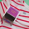Na obrazie widnieje pieczątka do ubrań z napisem 'Clothing Stamp', umieszczona na koszuli w czerwone paski. Na koszuli znajduje się metka z napisem 'LAURA BAYARD'. Pieczątka pochodzi od marki 'Avery'.