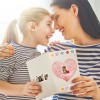 Radosny moment między matką a córką, obie uśmiechnięte, dzielące się kartką z życzeniami ozdobioną naklejkami w kształcie serca i zwierząt.